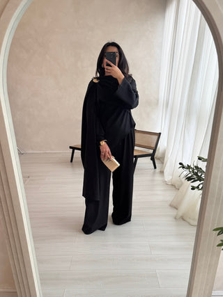 Elegant black cape top coord with a gold brooch, featuring a modest cape-style top and flowy trousers. Perfect for Eid abayas, wedding guest gowns, and modest fashion lovers.